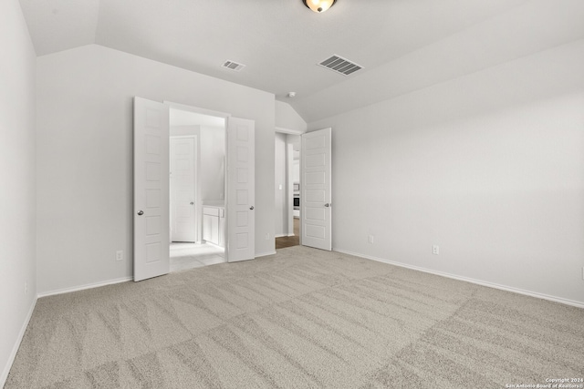 unfurnished bedroom featuring light colored carpet and lofted ceiling