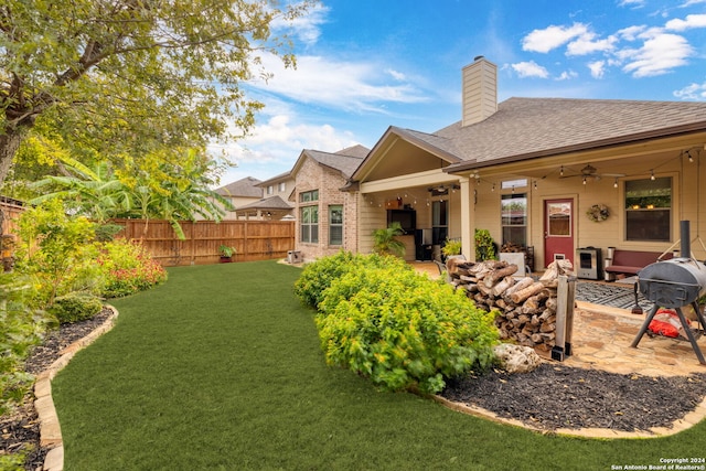 rear view of property featuring ceiling fan, a patio area, and a yard