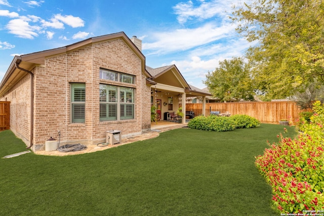 back of house with a lawn and a patio