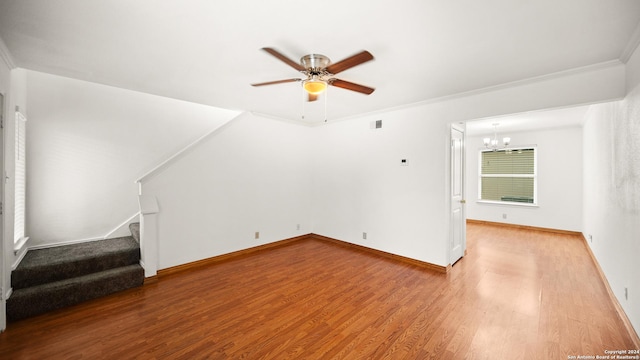 unfurnished living room featuring ceiling fan with notable chandelier, light wood-type flooring, and crown molding