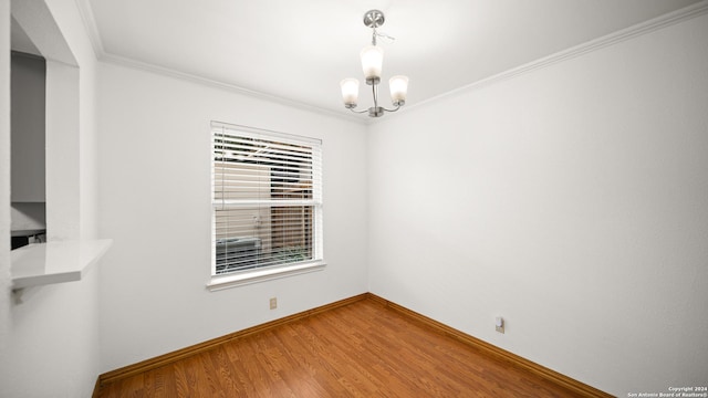 spare room with hardwood / wood-style floors, ornamental molding, and a chandelier