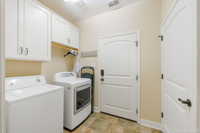 clothes washing area with washer and clothes dryer and cabinets