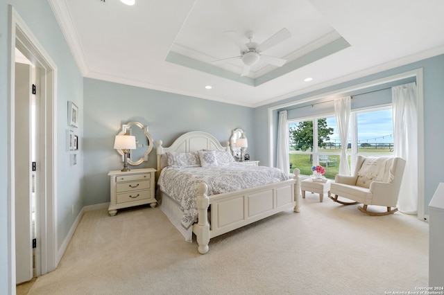 carpeted bedroom with a tray ceiling, ceiling fan, and ornamental molding