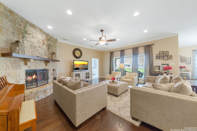 living room with dark hardwood / wood-style flooring, a stone fireplace, ceiling fan, and crown molding