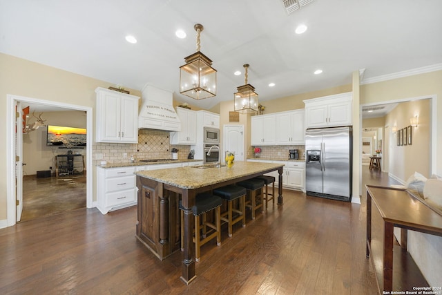 kitchen with light stone countertops, appliances with stainless steel finishes, white cabinetry, and an island with sink