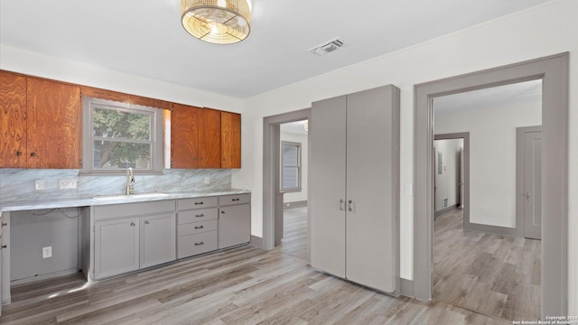 603 E Cedar St, Seguin, TX 78155 - kitchen featuring a sink, light wood-style flooring, gray cabinets, decorative backsplash, and brown cabinets