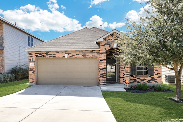 view of front of property featuring central AC unit, a garage, and a front lawn