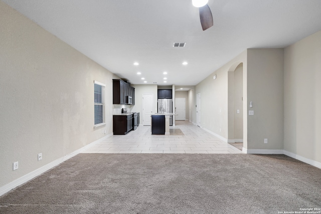 unfurnished living room featuring ceiling fan and light carpet