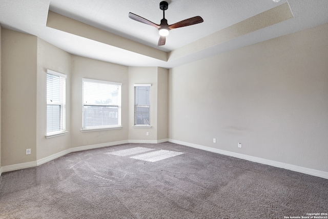 carpeted spare room featuring ceiling fan, a textured ceiling, and a tray ceiling