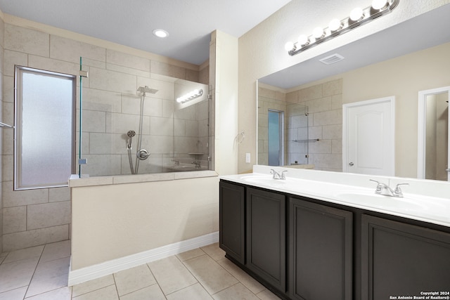 bathroom with tile patterned floors, vanity, and tiled shower