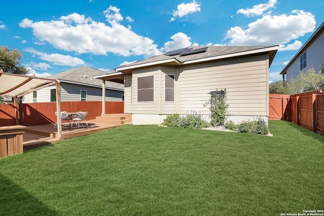 back of house with a lawn, solar panels, and a deck