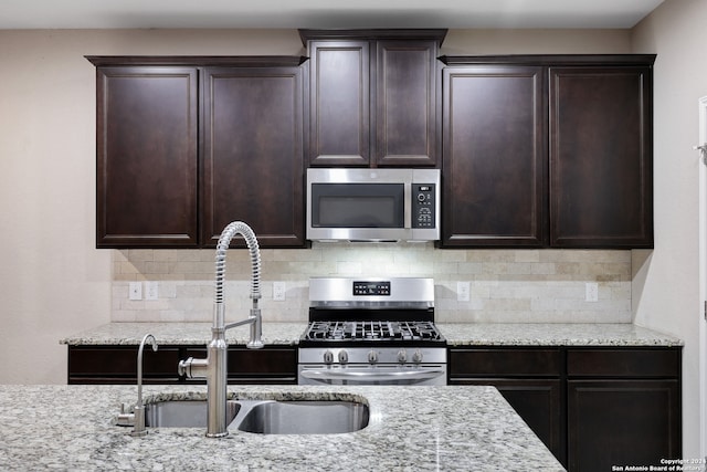 kitchen featuring decorative backsplash, sink, light stone counters, and appliances with stainless steel finishes