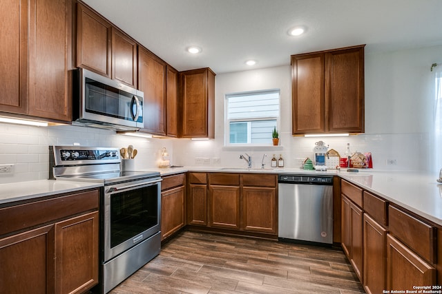 kitchen featuring backsplash, sink, stainless steel appliances, and dark wood-type flooring