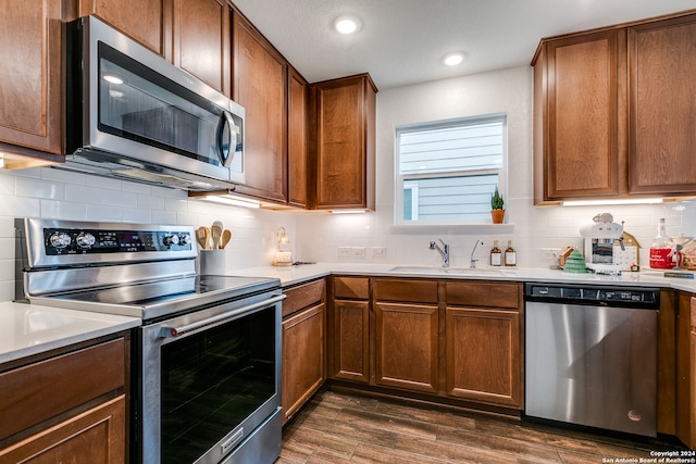 kitchen with decorative backsplash, dark hardwood / wood-style flooring, a textured ceiling, stainless steel appliances, and sink