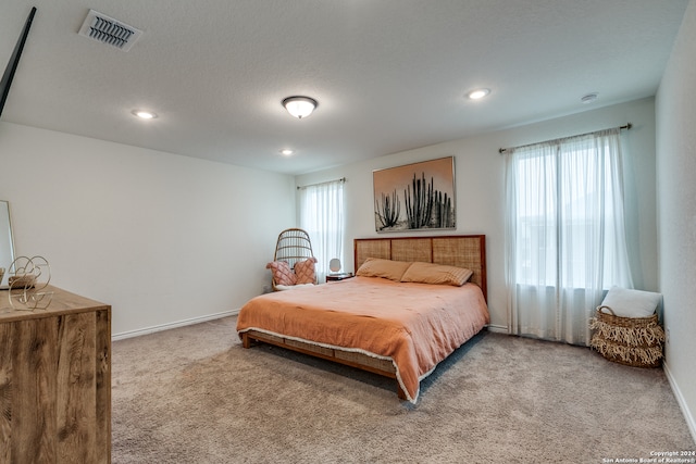 carpeted bedroom featuring a textured ceiling and multiple windows