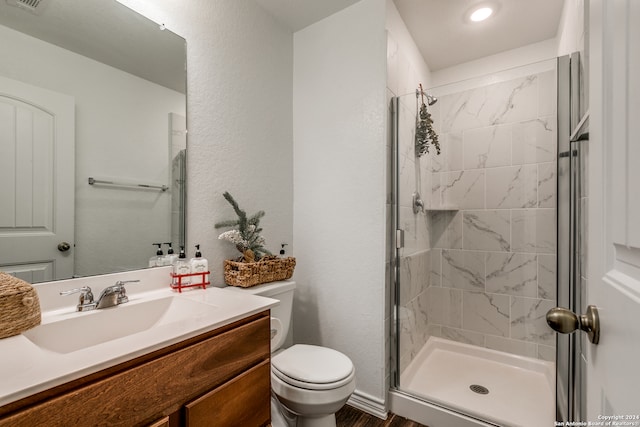 bathroom featuring a shower with door, vanity, and toilet