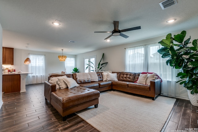 living room featuring dark hardwood / wood-style floors, a textured ceiling, and ceiling fan with notable chandelier