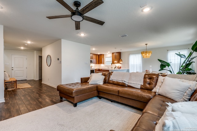 living room featuring ceiling fan with notable chandelier and hardwood / wood-style flooring