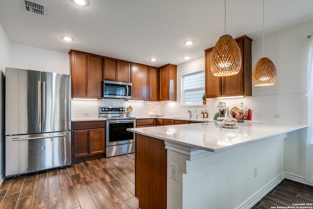 kitchen featuring kitchen peninsula, decorative backsplash, stainless steel appliances, dark wood-type flooring, and decorative light fixtures