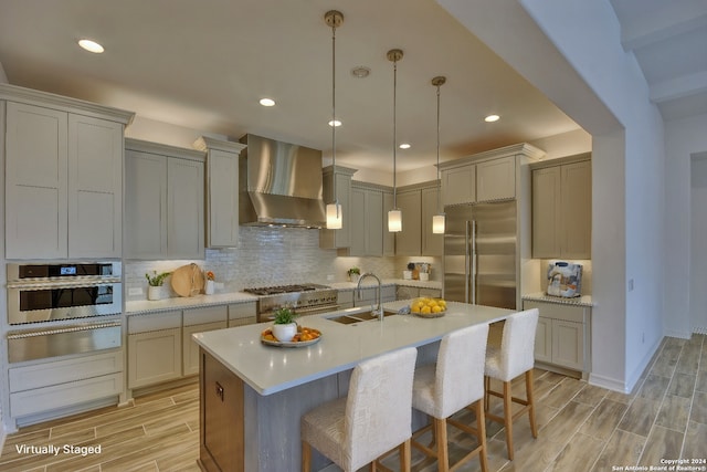 kitchen featuring premium appliances, wall chimney range hood, sink, and light hardwood / wood-style flooring