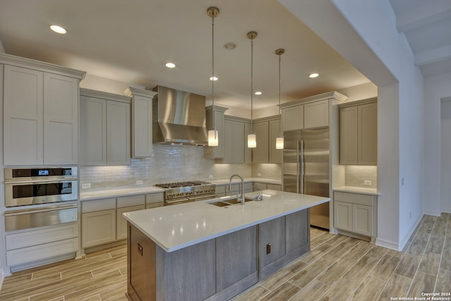 kitchen featuring sink, wall chimney range hood, high quality appliances, decorative backsplash, and light wood-type flooring