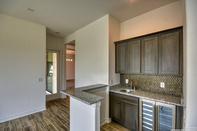 kitchen featuring dark wood-type flooring, sink, wine cooler, dark stone countertops, and dark brown cabinetry