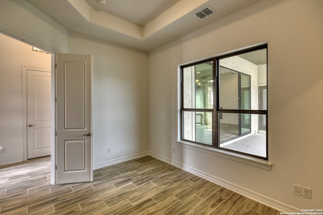 empty room with a raised ceiling and wood-type flooring