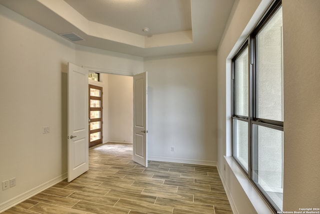 empty room featuring light hardwood / wood-style floors and a raised ceiling