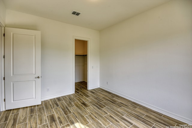 unfurnished bedroom featuring a walk in closet, a closet, and wood-type flooring