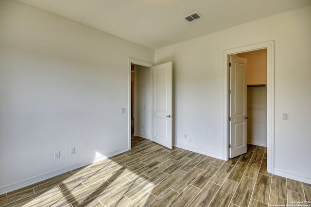 unfurnished bedroom with light hardwood / wood-style floors and a spacious closet