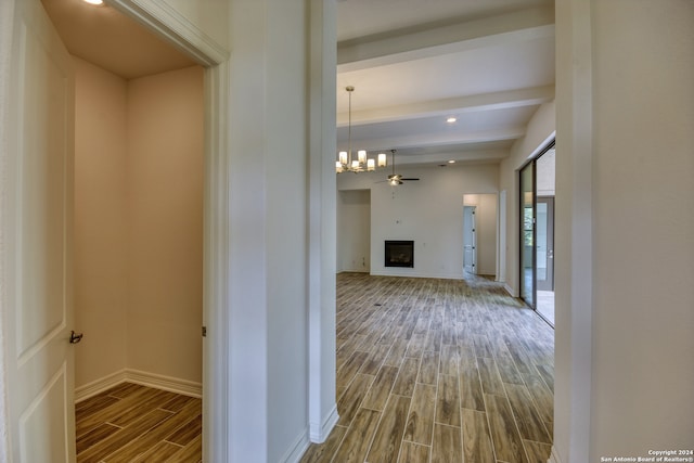 hallway with an inviting chandelier, beamed ceiling, and hardwood / wood-style flooring