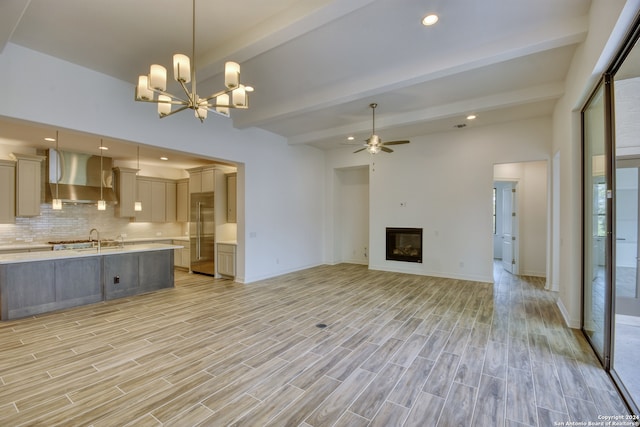 unfurnished living room with beam ceiling, ceiling fan with notable chandelier, light hardwood / wood-style floors, and sink