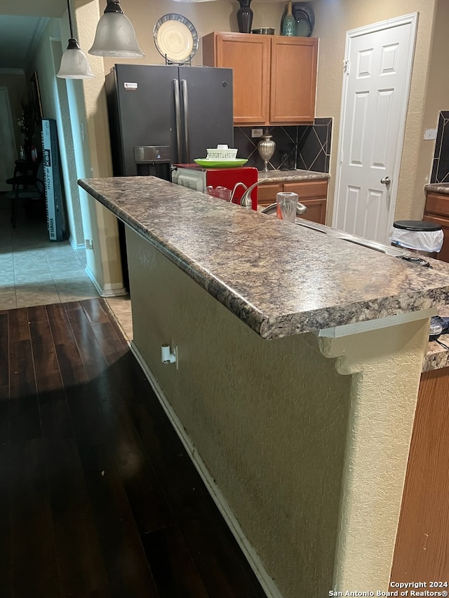 kitchen featuring tasteful backsplash, refrigerator with ice dispenser, and hardwood / wood-style flooring