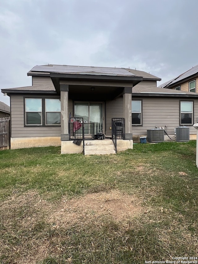 rear view of property featuring a patio area, a yard, central AC unit, and solar panels