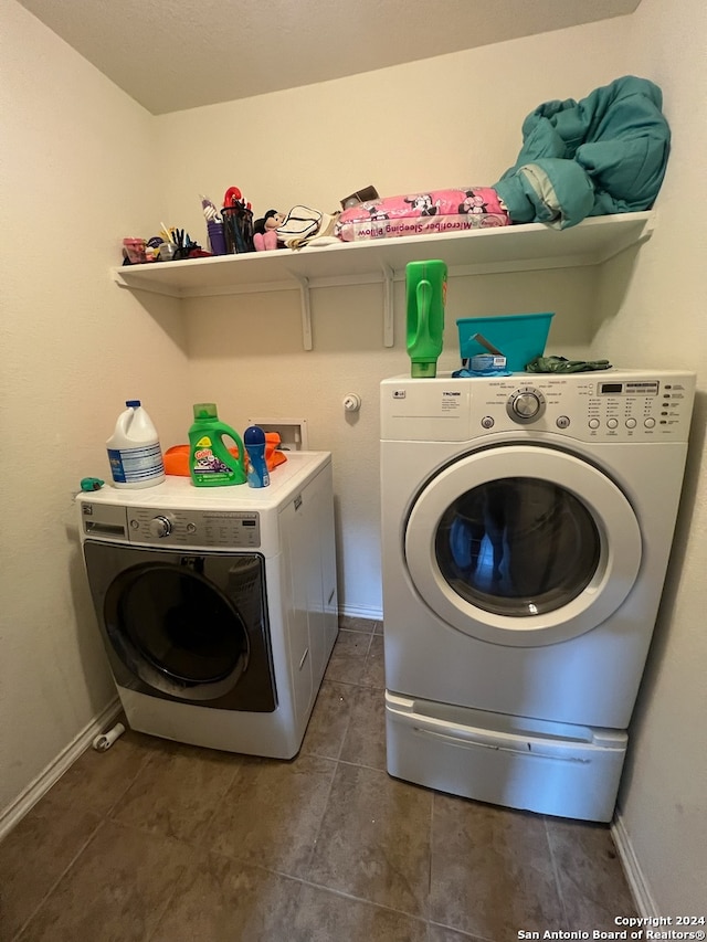 laundry area featuring washer and dryer and dark tile patterned flooring