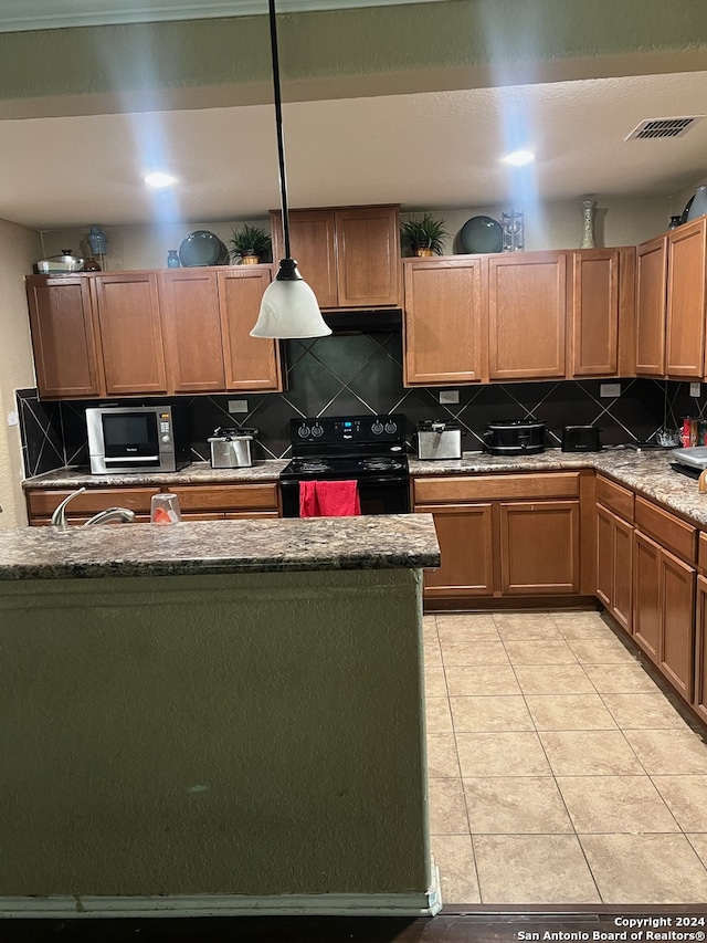 kitchen featuring electric range, light stone counters, backsplash, decorative light fixtures, and light tile patterned flooring