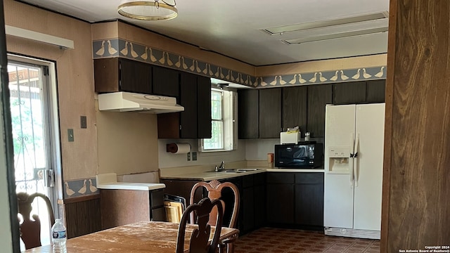 kitchen with dark brown cabinets, white fridge with ice dispenser, and sink