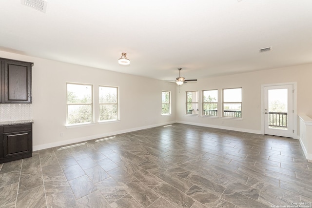 unfurnished living room featuring ceiling fan and a healthy amount of sunlight