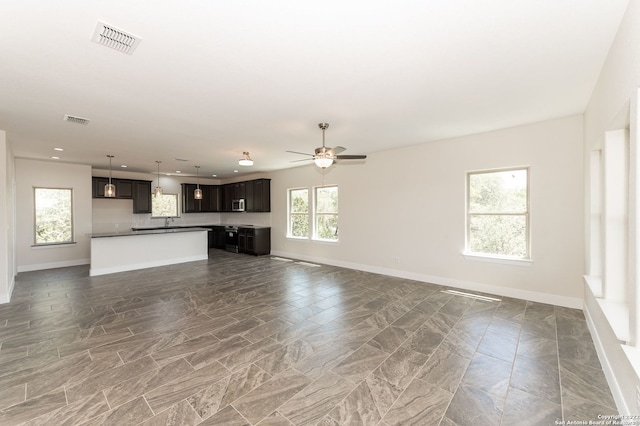 unfurnished living room featuring ceiling fan and a healthy amount of sunlight