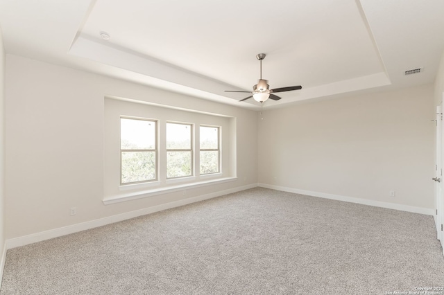 spare room featuring carpet, ceiling fan, and a raised ceiling