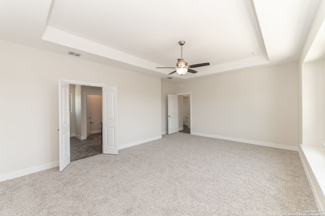 unfurnished bedroom featuring a tray ceiling, ceiling fan, and carpet floors