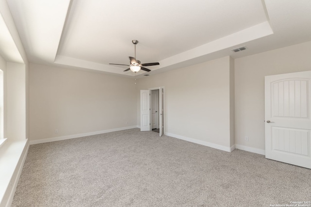 spare room featuring a tray ceiling, ceiling fan, and light colored carpet