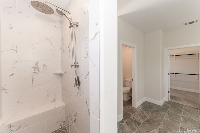 bathroom featuring a tile shower and toilet