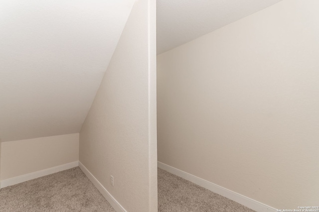 interior space with light carpet and vaulted ceiling