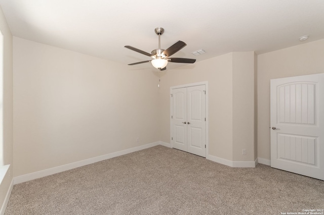 unfurnished bedroom featuring ceiling fan, light colored carpet, and a closet