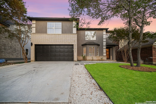 front facade featuring a garage and a lawn