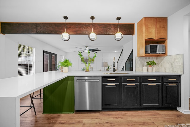 kitchen featuring light hardwood / wood-style flooring, stainless steel appliances, decorative light fixtures, and sink