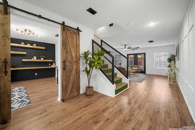 interior space featuring a barn door, hardwood / wood-style flooring, and ceiling fan