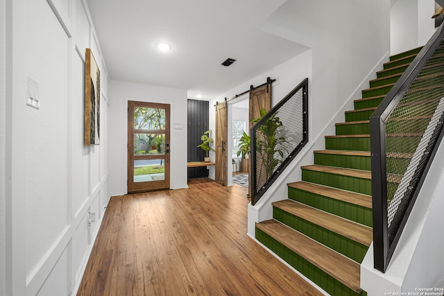 entrance foyer with a barn door and light hardwood / wood-style floors