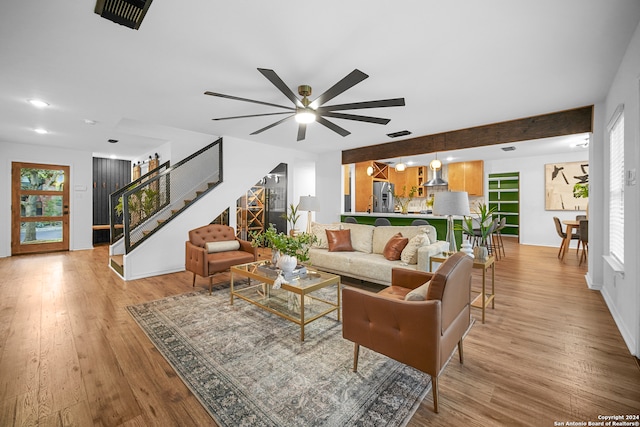 living room with beam ceiling, ceiling fan, and light hardwood / wood-style flooring